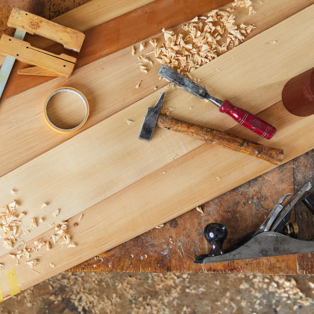 Mehrere Werkzeuge für Holzbearbeitung liegen auf Brettern.