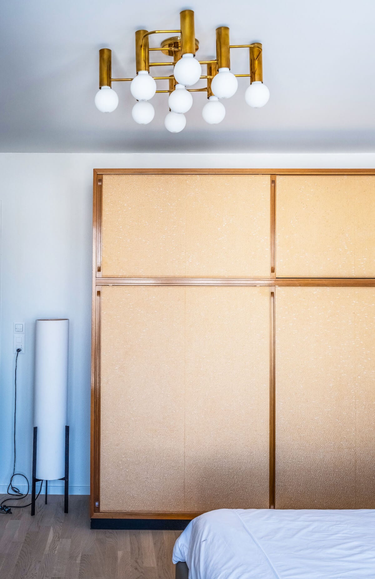 Goldiger Deckenkronleuchter und Holzschrank in einem Schlafzimmer.