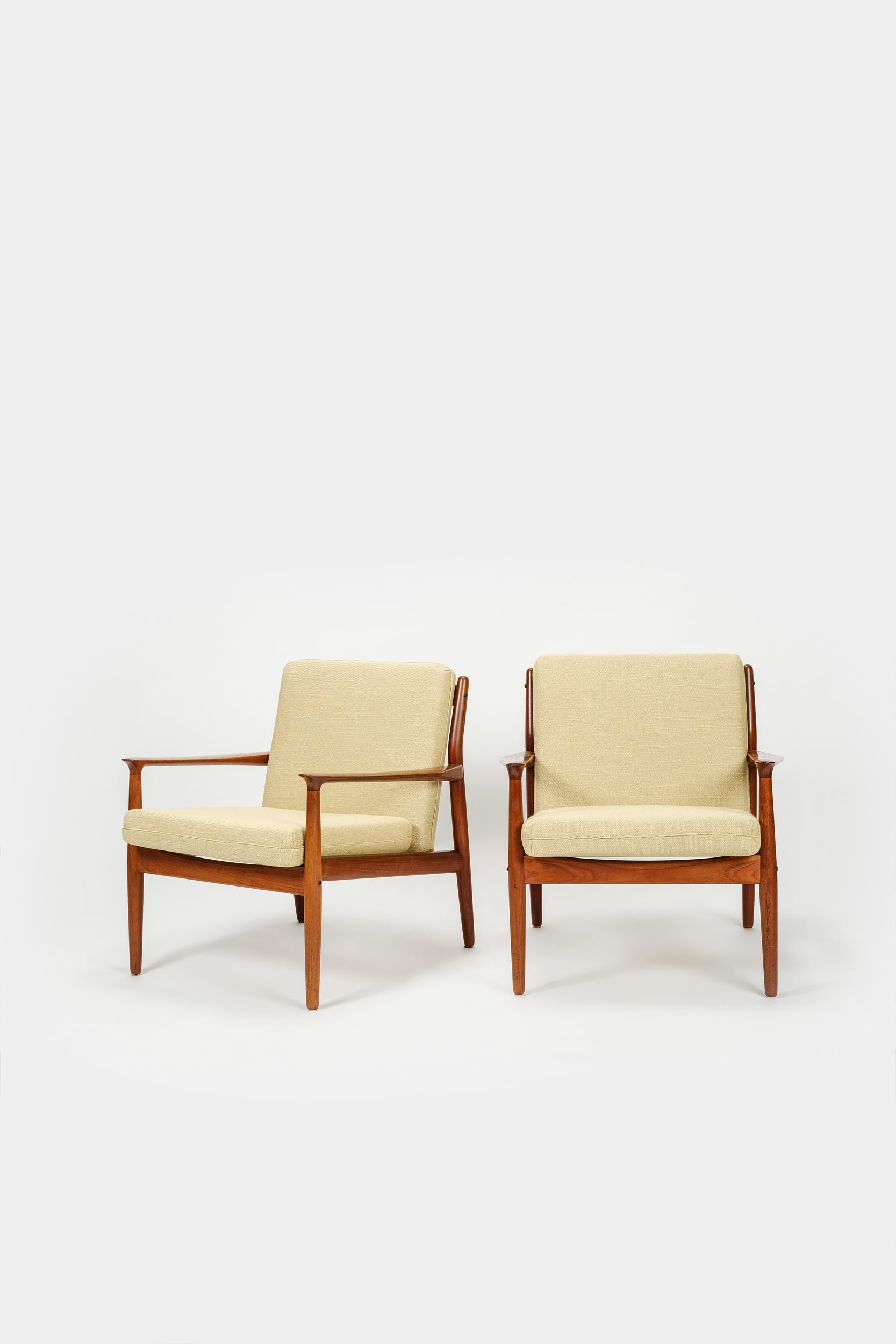 Two beautiful teak armchairs from the 50s, Denmark, designed by Svend Aage Eriksen for the company Glostrup Møbelfabrik. The frame of the armchairs is made of solid teak, the cushions are freshly upholstered with grey flannel fabric framed with leather piping. With additional cushions with light yellow cotton fabric. A total of 8 cushions. Very nice condition.  Dimensions Width: 67 cm | Length: 72 cm | Height: 75 cm  Seat height: 38 cm