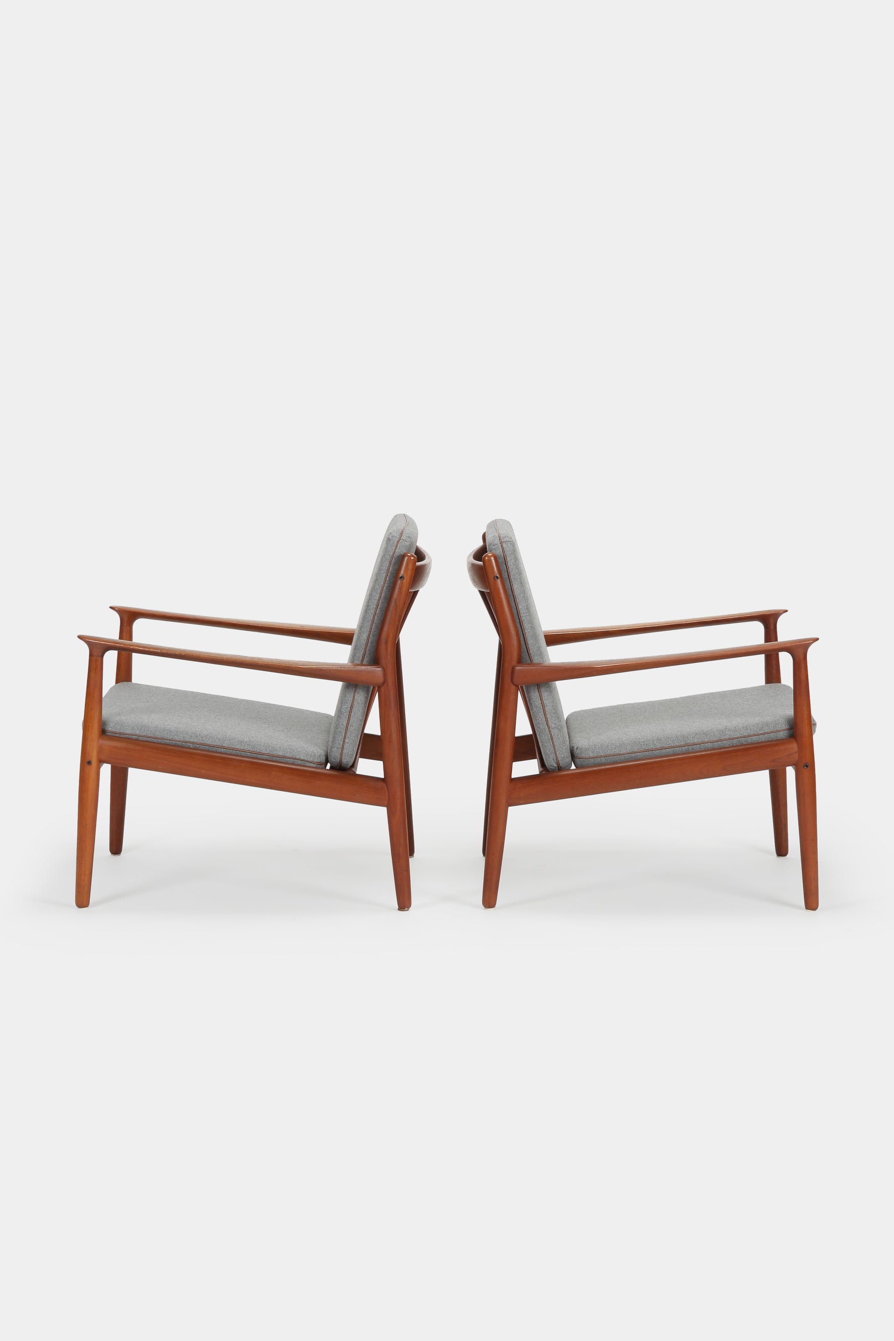 Two beautiful teak armchairs from the 50s, Denmark, designed by Svend Aage Eriksen for the company Glostrup Møbelfabrik. The frame of the armchairs is made of solid teak, the cushions are freshly upholstered with grey flannel fabric framed with leather piping. With additional cushions with light yellow cotton fabric. A total of 8 cushions. Very nice condition.  Dimensions Width: 67 cm | Length: 72 cm | Height: 75 cm  Seat height: 38 cm